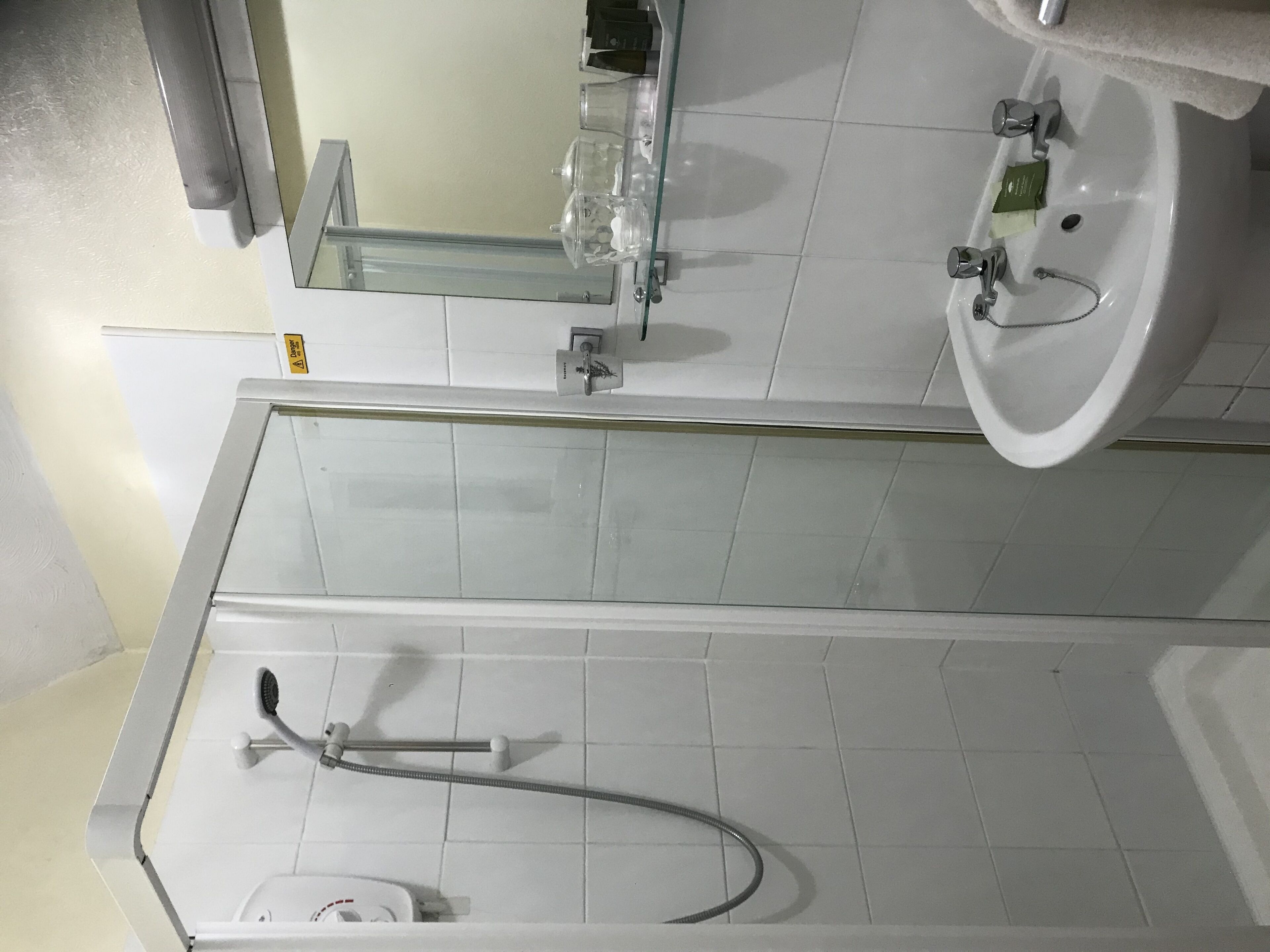 Un baño con cabina de ducha de vidrio, un lavabo blanco y un espejo sobre el lavabo.