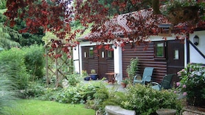 A garden with a wooden house, stone benches, and potted plants. - West Lodge Hotel (Aylesbury)