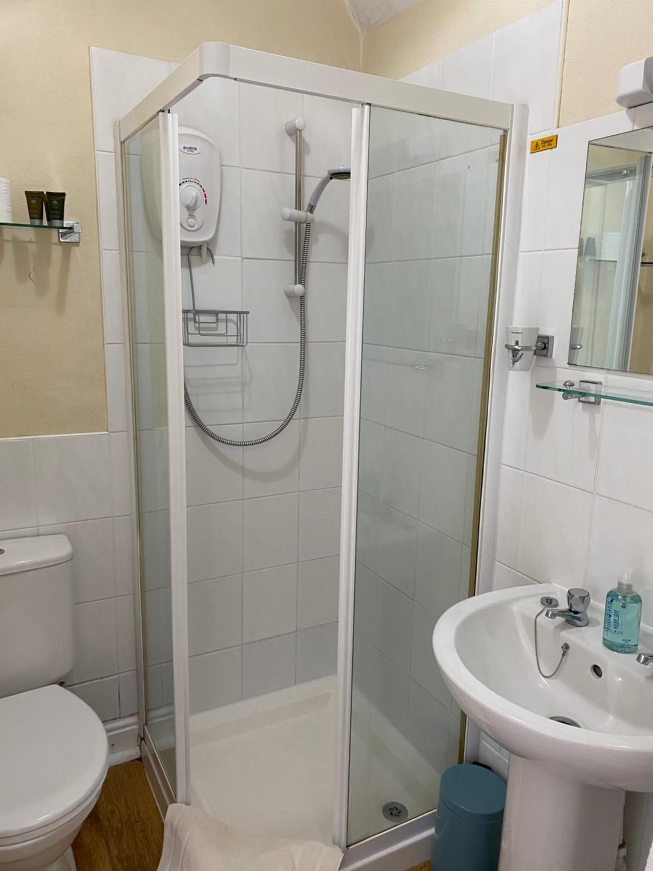 Een badkamer met een douchecabine van glas, een wit wastafelmeubel en een toilet.