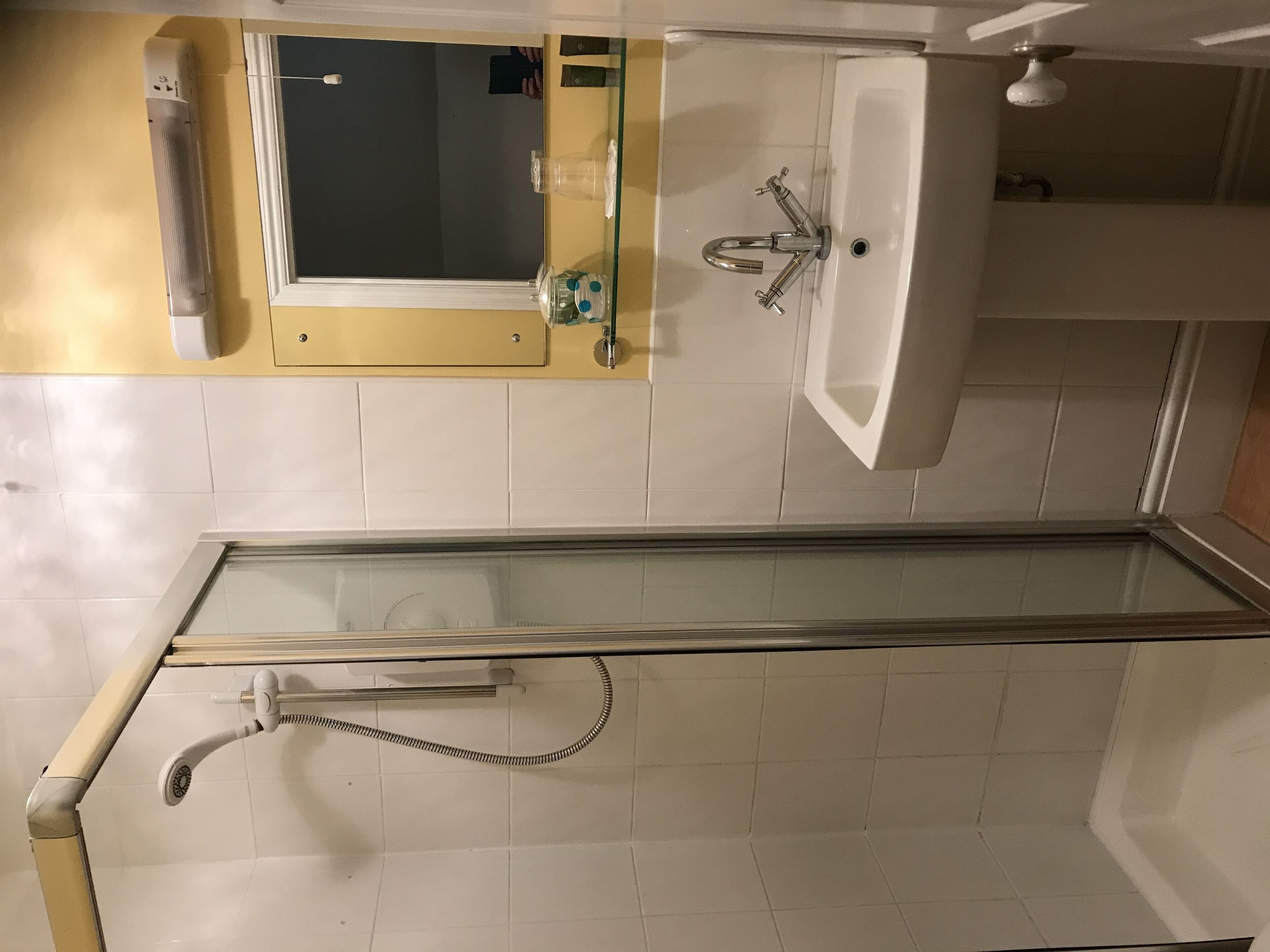 Une salle de bain avec une douche à parois de verre, un lavabo et un miroir.