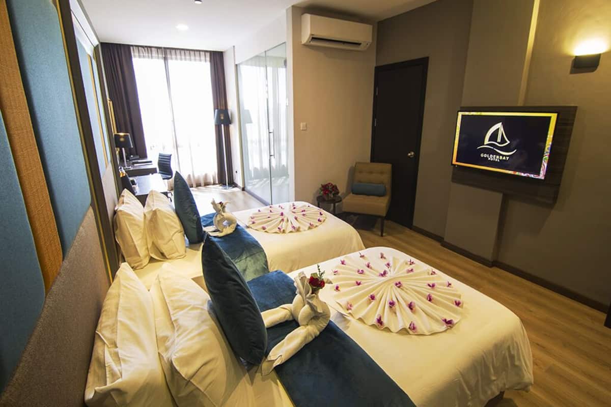 A hotel room with two beds, a TV, a piano, and a view of the outside.