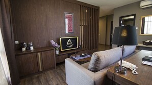 Een moderne hotelkamer met een bank, een bureau met lamp, een televisie en een minibar.
