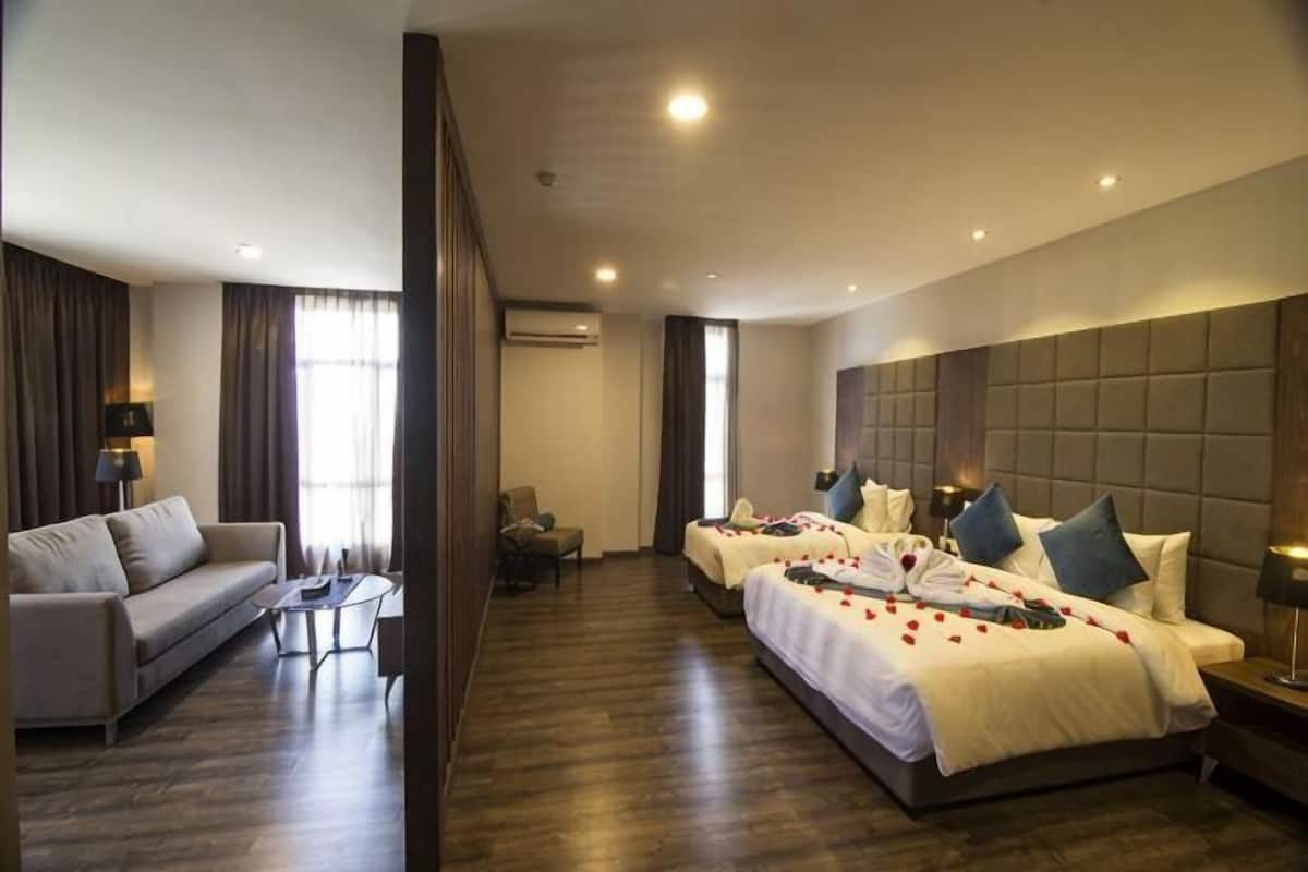 A hotel room with a large bed, a sofa, a small table, and a chair.