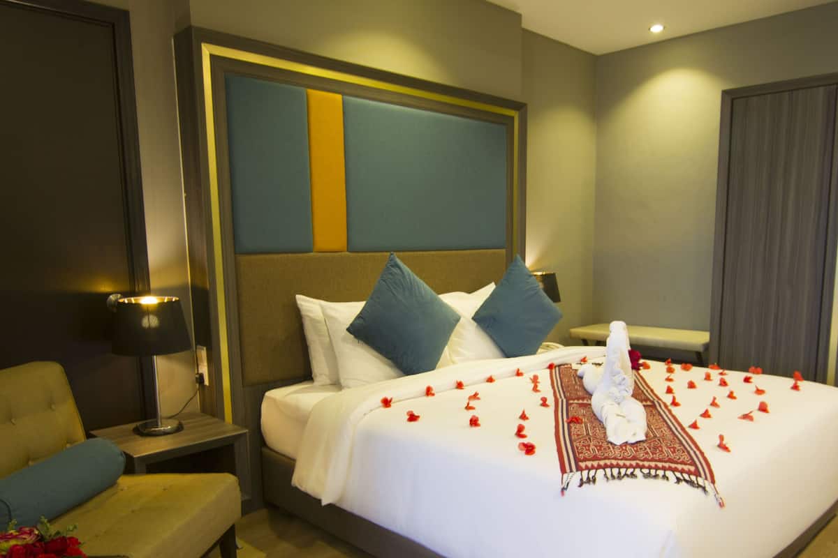 A hotel room with a large bed, a bedside table with a lamp, a chair, and a view of the outside.