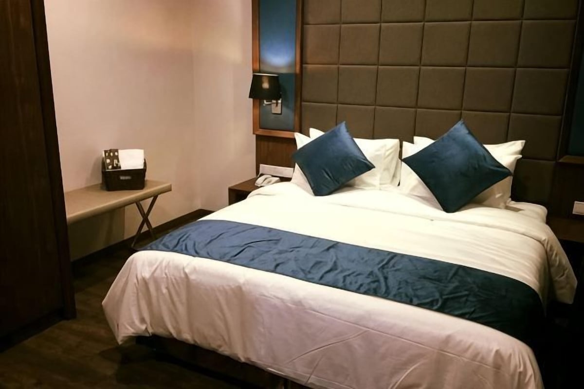 Ein Hotelzimmer mit Bett, Nachttisch, Lampe und einem Beistelltisch.