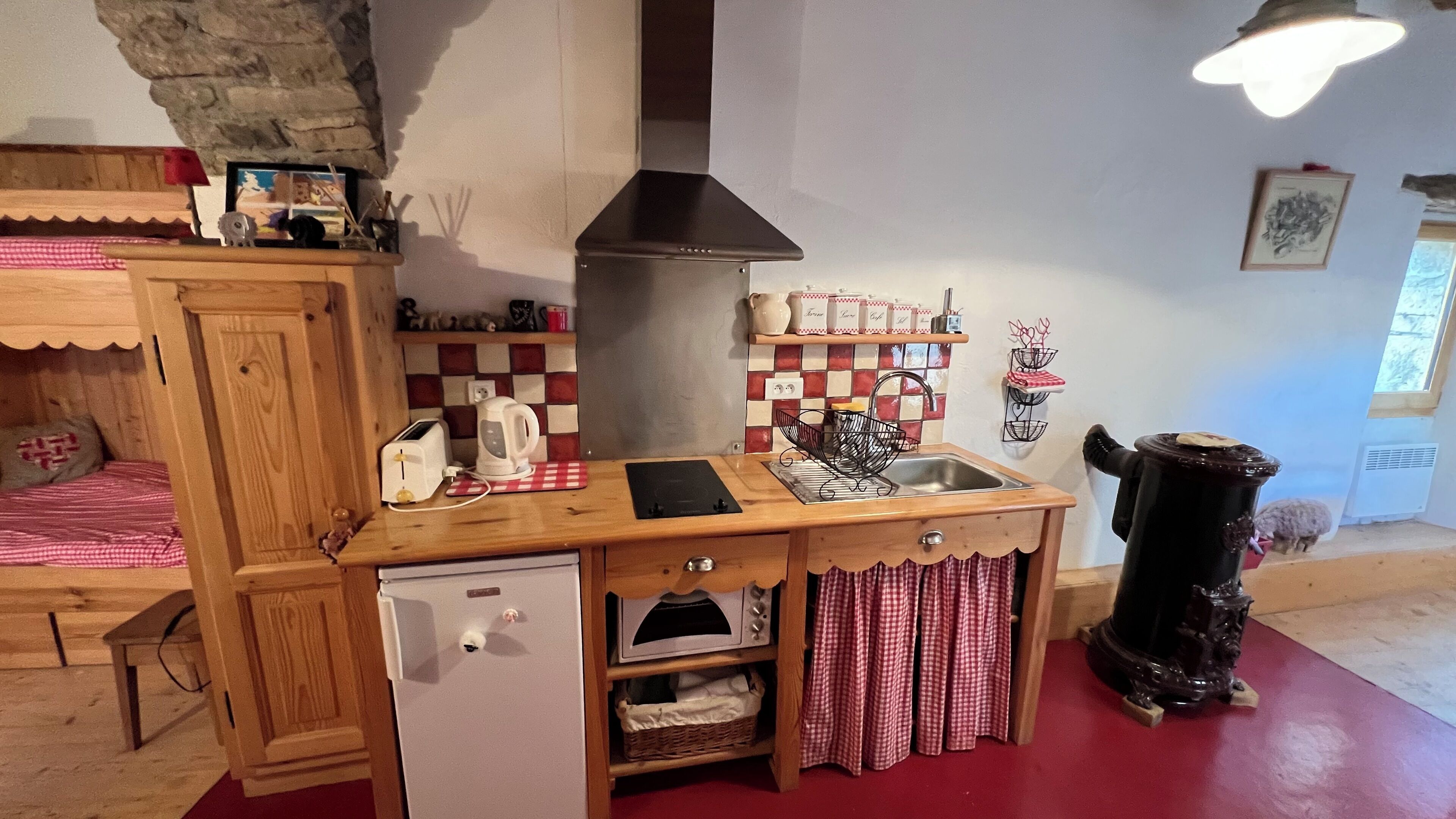 A compact kitchen with a wooden countertop, a built-in dishwasher, and a red and white checkered tablecloth.
