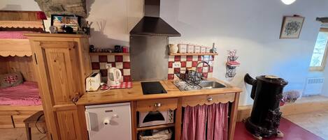 A compact kitchen with a wooden countertop, a built-in dishwasher, and a red and white checkered tablecloth.