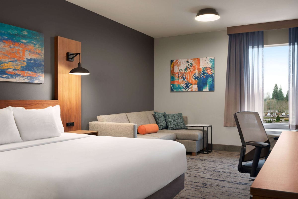 Ein Hotelzimmer mit Bett, Sofa, Schreibtisch und Fenster mit Blick.