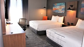 Una habitación de hotel con dos camas, un escritorio, una silla y un televisor.
