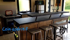 Une cuisine moderne dotée d’un îlot central, de tabourets de bar et offrant une vue sur le jardin.