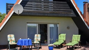Een modern gebouw met een schuin dak, een schotelantenne en een patio met stoelen en een tafel.