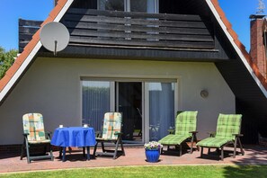 En moderne bygning med skråt tag, parabolantenne og en patio med stole og et bord.