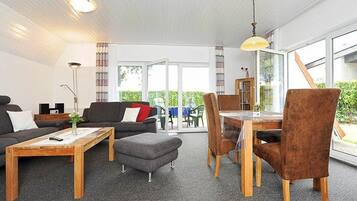 Een moderne woonkamer met een bank, salontafel en een eethoek.