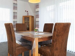 A dining area with a wooden table and four brown chairs. - Ferienhaus am Tief in Neuharlingersiel - Ferienhaus am Tief (Neuharlingersiel)