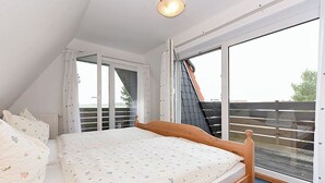 Een slaapkamer met een bed, een raam en uitzicht op het omliggende landschap.
