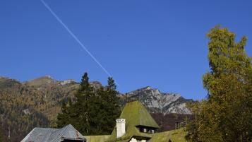 A mountain village with traditional houses, a clear sky, and a visible contrail.