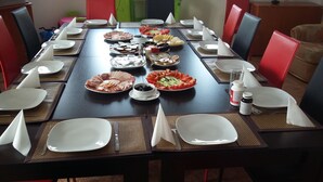A dining table set for a meal with various dishes, plates, and cutlery. - Pensiunea Nicolas (Sinaia)