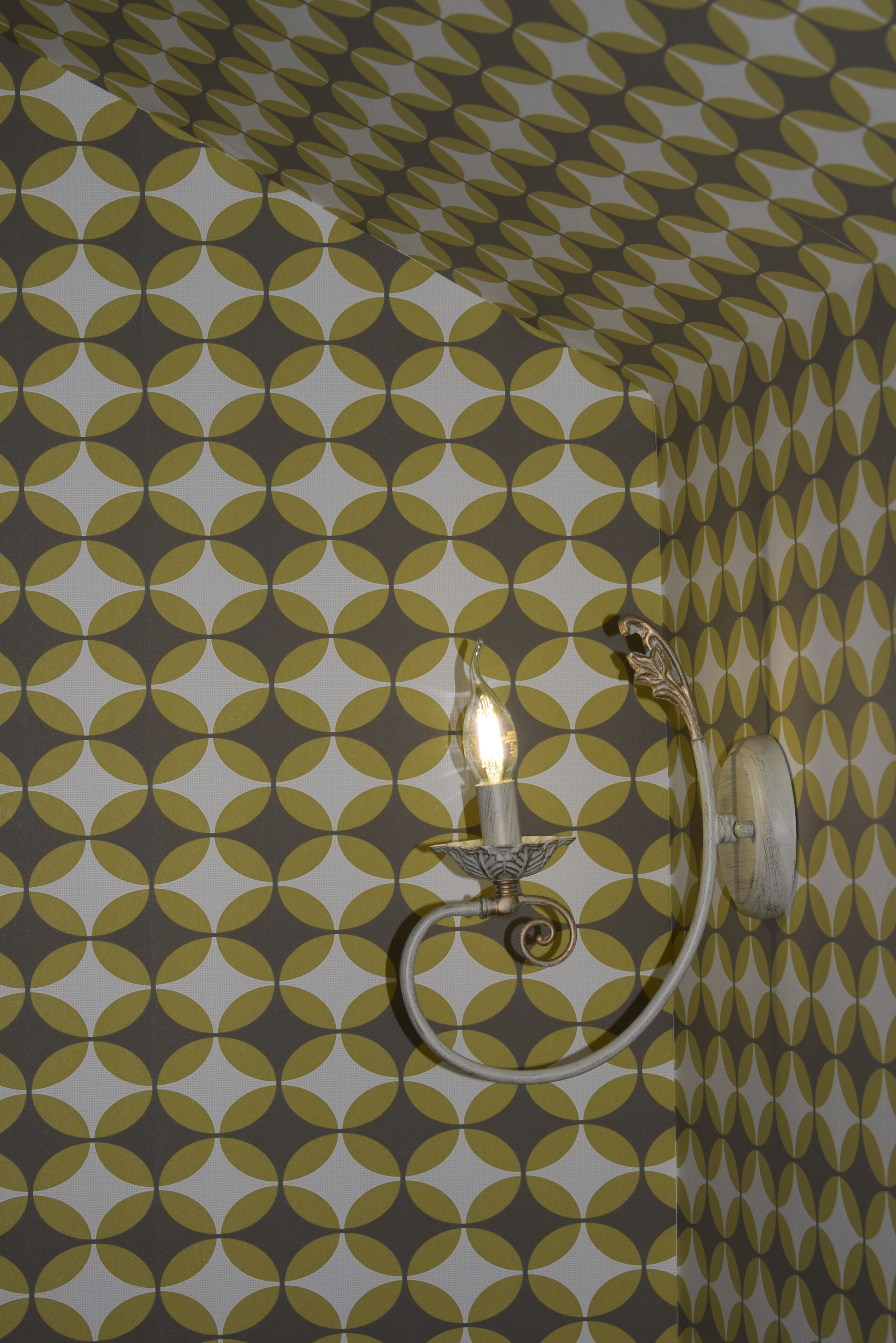 A wall with a geometric pattern and a wall-mounted light fixture.