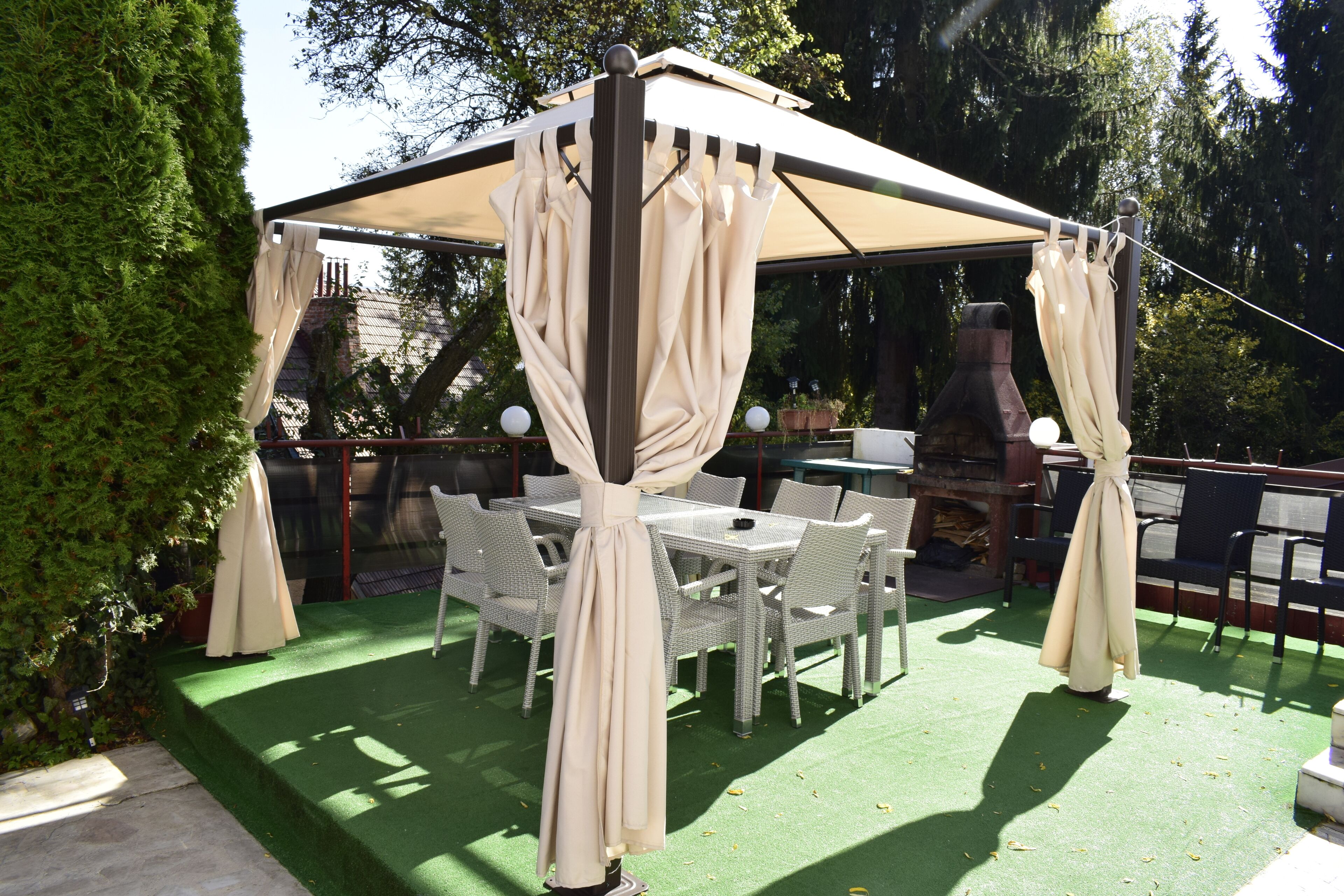 An outdoor patio with a covered seating area, green artificial turf, and white wicker furniture.