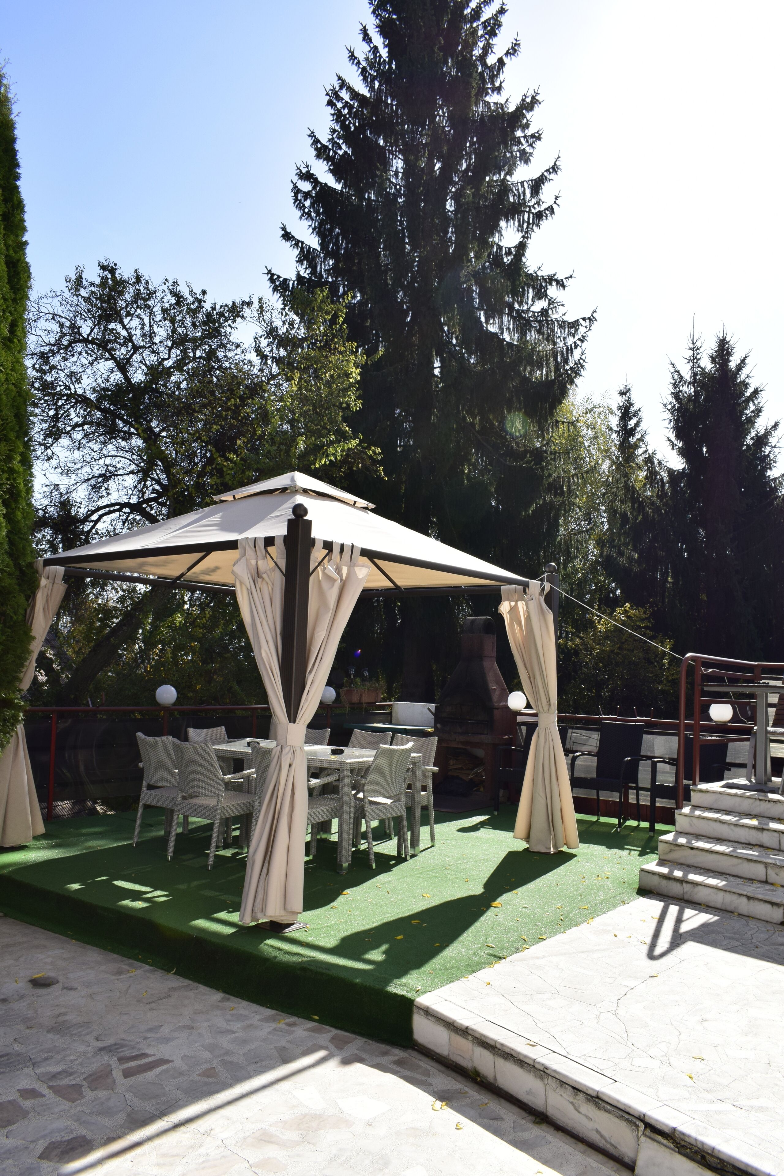 Un patio al aire libre con toldo, sillas de mimbre y suelo de piedra.