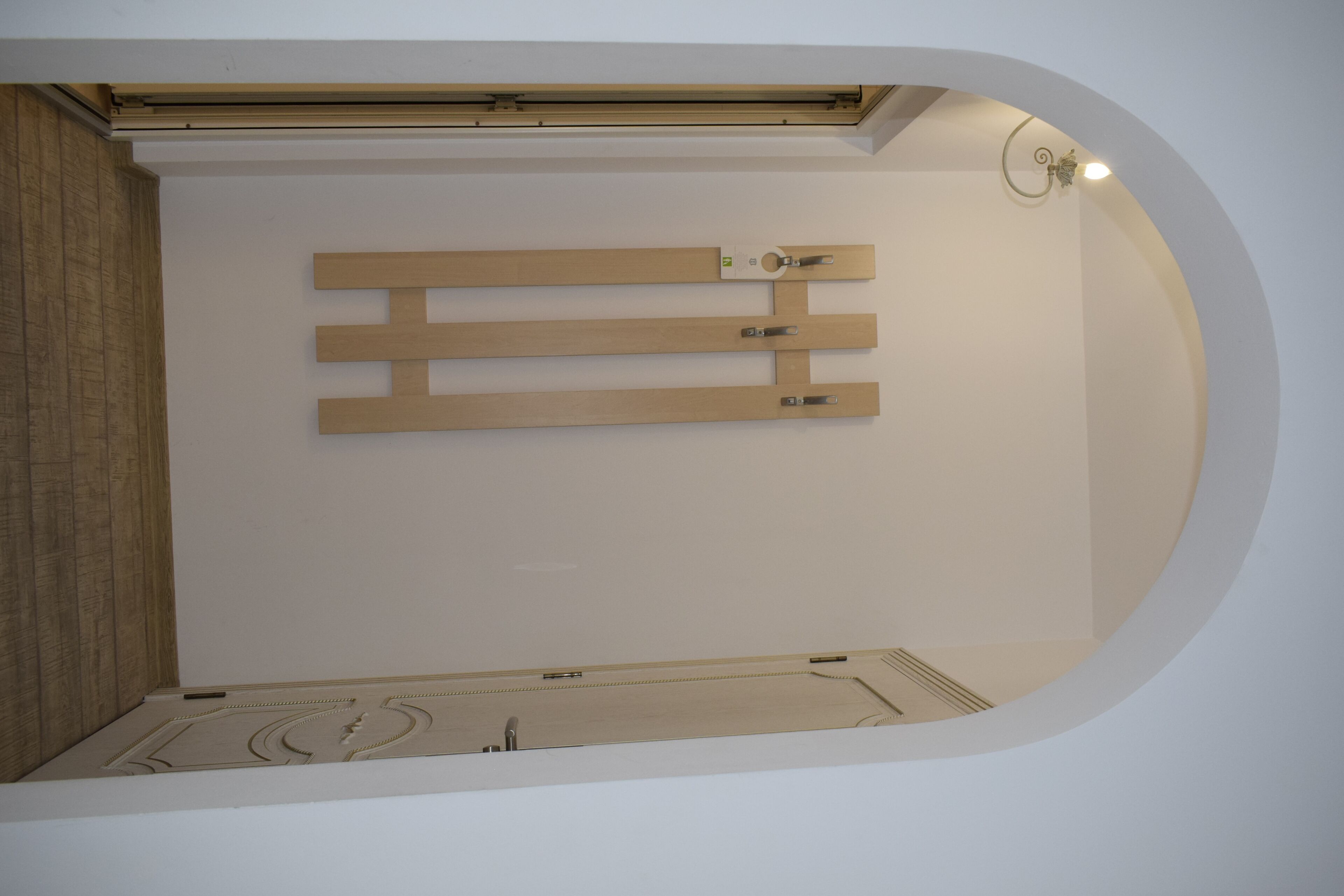 A room with a wooden slat wall design, a ceiling light fixture, and a recessed ceiling.