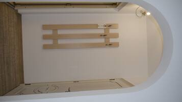 A room with a wooden slat wall design, a ceiling light fixture, and a recessed ceiling.