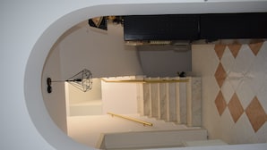 A modern interior with a staircase, a kitchen area, and a unique wall design. - Pensiunea Nicolas (Sinaia)
