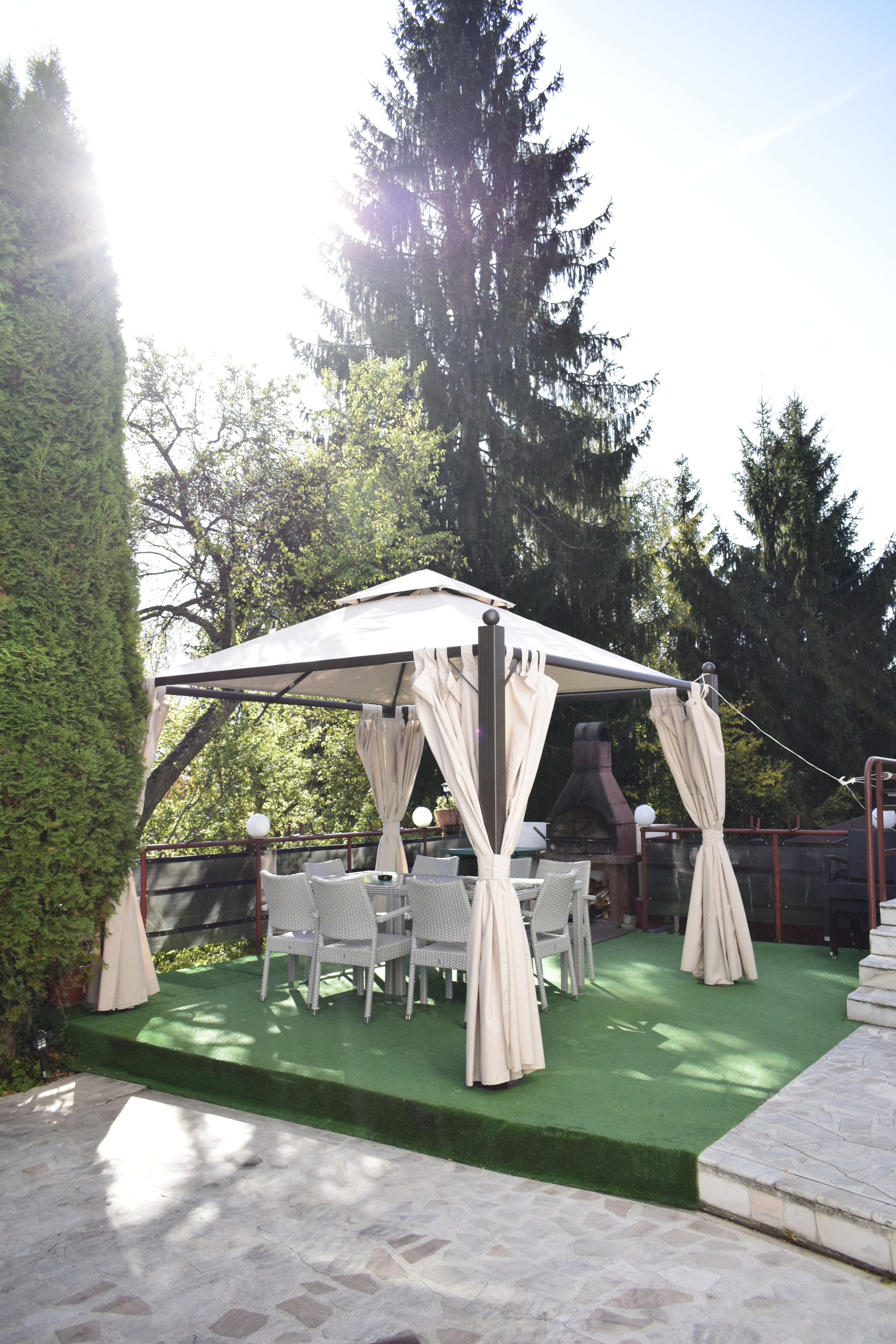 An outdoor patio with a covered seating area, green artificial turf, and white wicker furniture.