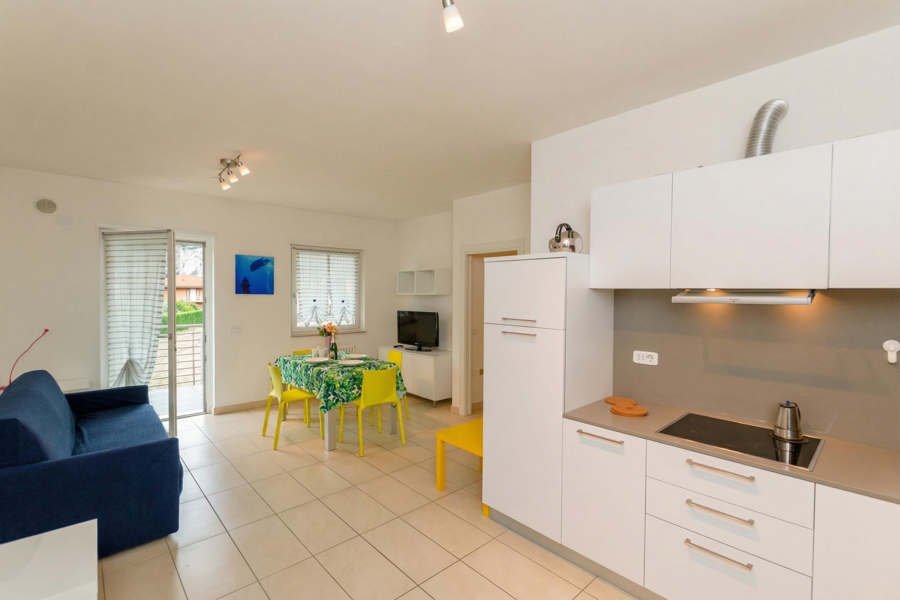 A modern kitchen with white cabinets, a built-in stove, and a dining area with a table and chairs.
