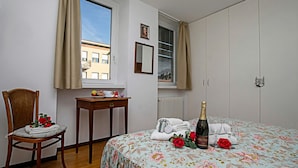 Une chambre à coucher comprenant un lit, une chaise, une table, une fenêtre et un radiateur.