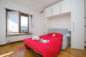 Ein Schlafzimmer mit Bett, Fenster, Heizkörper und Kleiderschrank.
