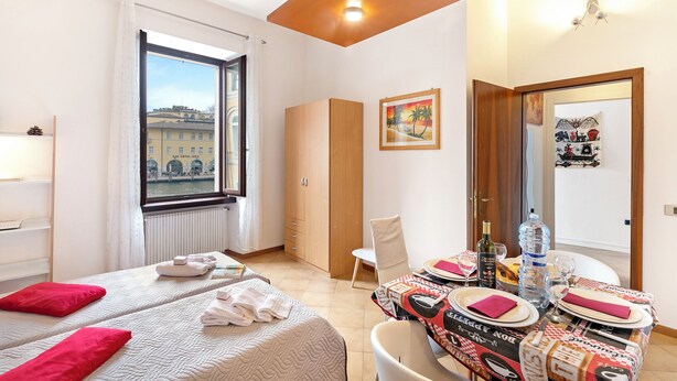 A hotel room with two beds, a dining table set with plates and glasses, a water bottle, and a bottle of wine.