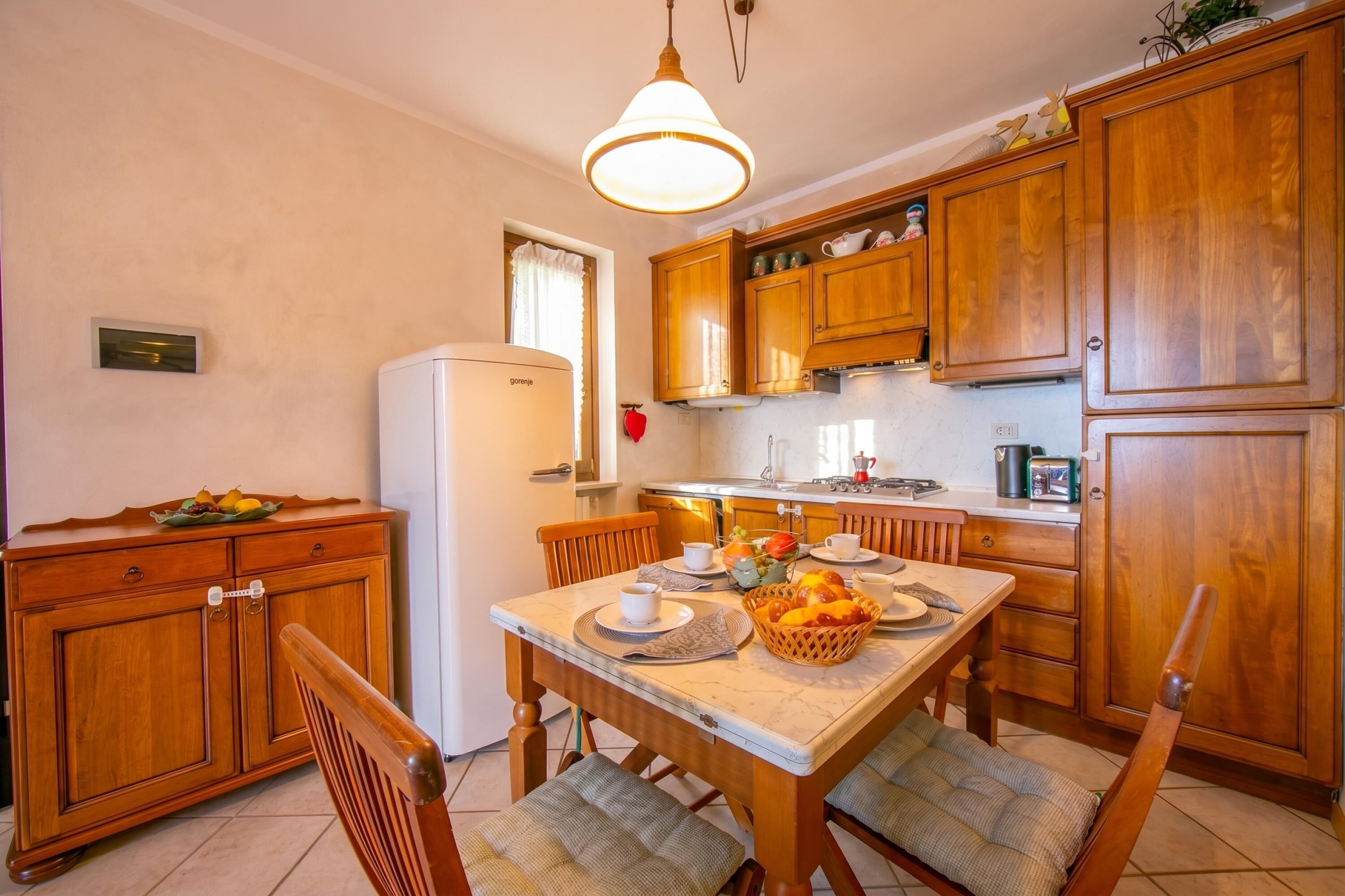 A kitchen with wooden cabinets, a dining table with chairs, and a refrigerator.