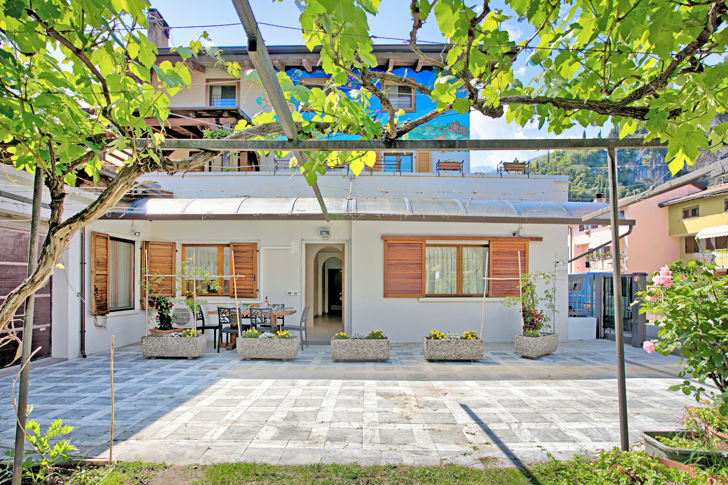 A two-story house with a patio area, outdoor furniture, and potted plants.