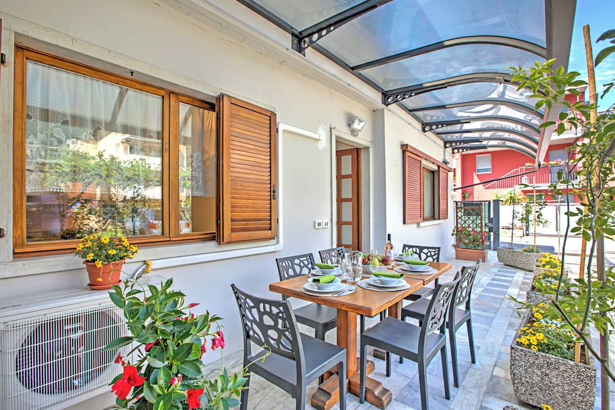A dining area with a table set for four, surrounded by chairs, and a window with wooden shutters.