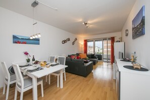 Enjoy a stylish living space with a dining area and seating area, featuring a table for two, a sofa, and a large window with a city view.