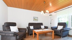Una sala de estar con dos sofás, una mesa de centro y techo de madera.