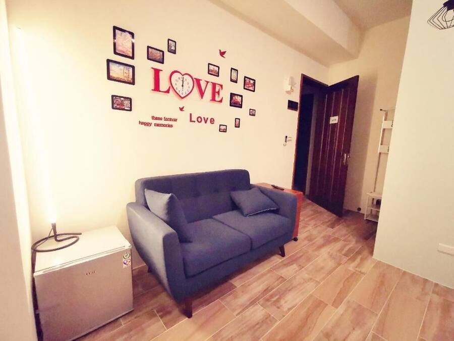 Una sala de estar con un sofá azul, una mesita y una pared decorada con los mensajes 'LOVE' y 'recuerdos felices'.