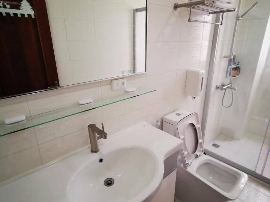 A modern bathroom with a white sink, a glass shower enclosure, and a toilet.