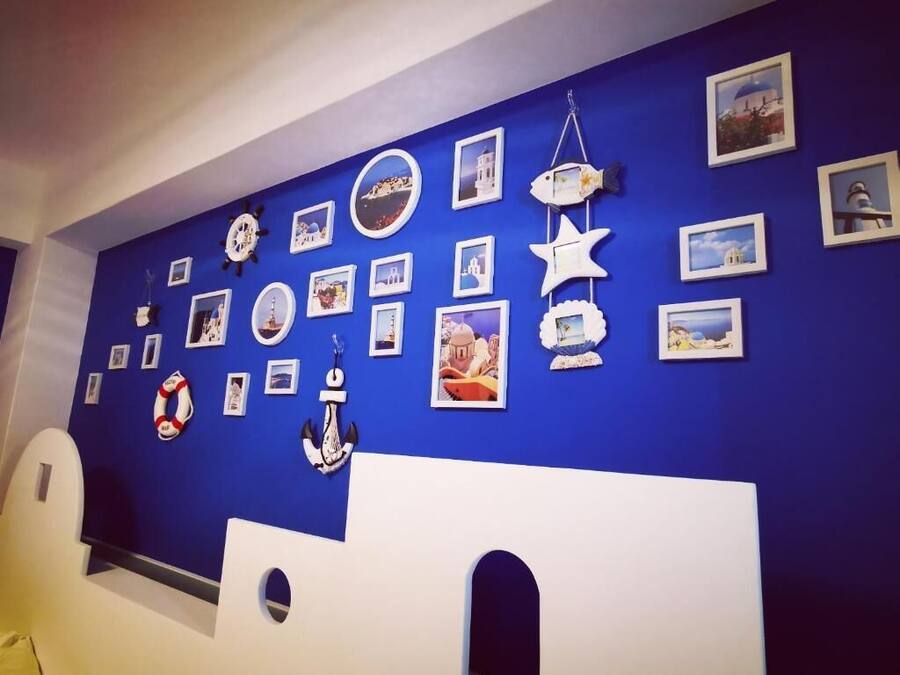 Quarto com parede azul decorada com motivos náuticos, incluindo quadros e objetos marítimos.