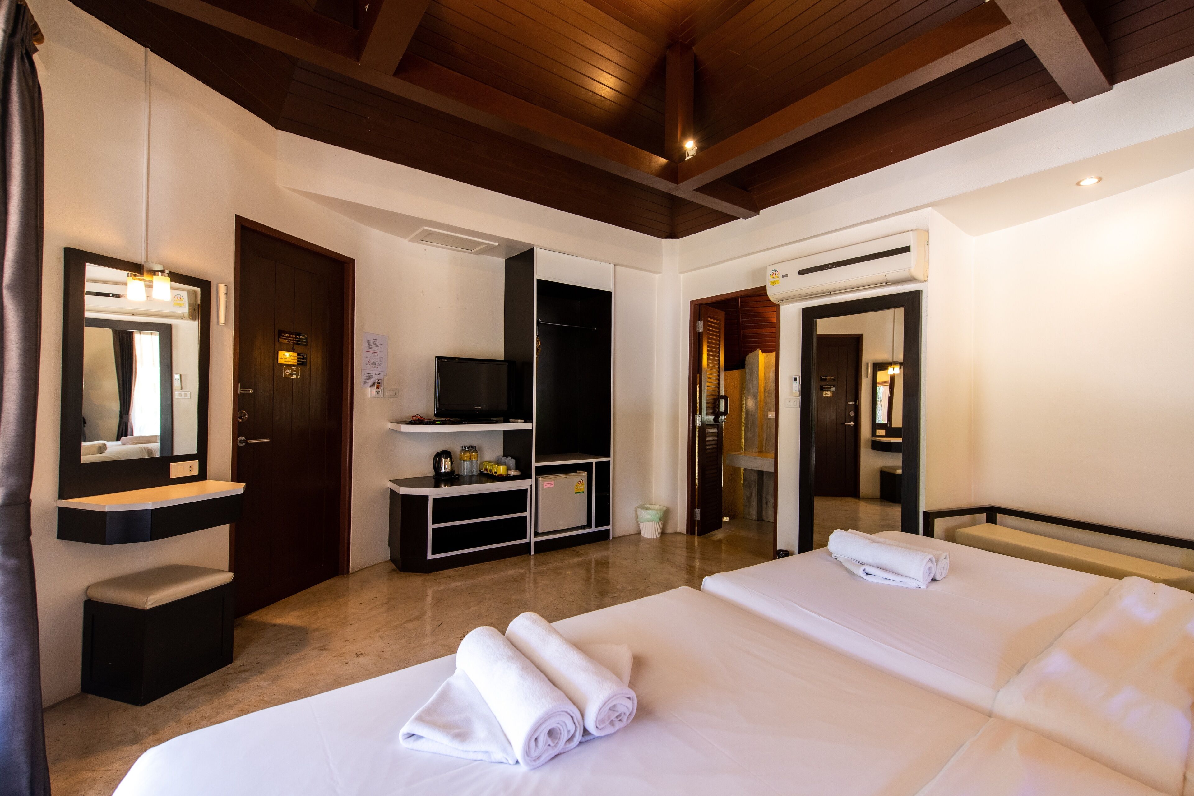 Habitación de hotel con dos camas, televisión, minibar y baño.