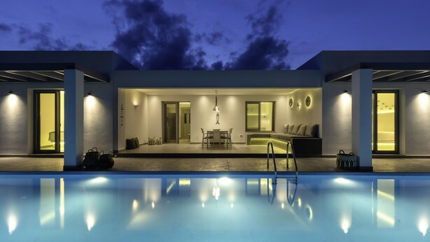 Ein modernes Haus mit Schwimmbad, Essbereich und Wohnzimmer mit Sofa und Couchtisch.