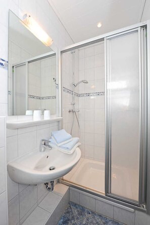 Een douche, handdoeken, zeep, toiletpapier