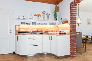 A modern kitchen with white cabinets, a curved countertop, and various kitchenware.