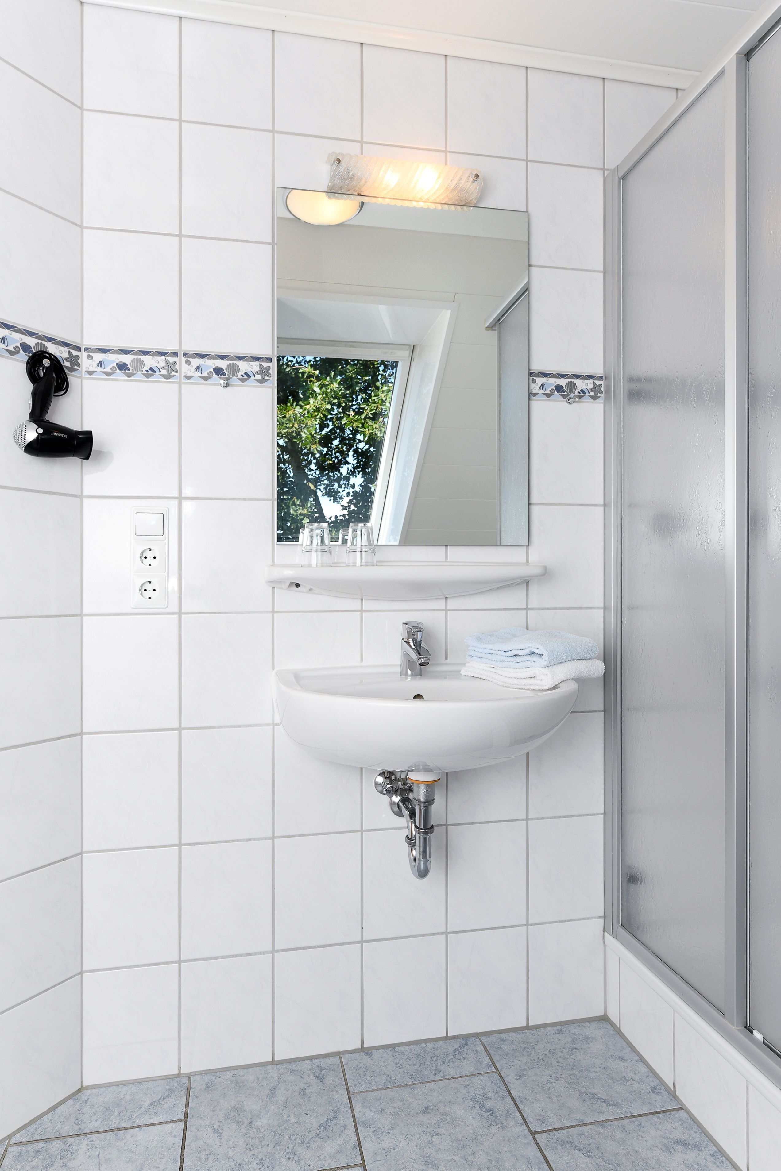 A modern bathroom with a white sink, mirror, and shower.