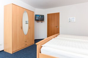 Une chambre à coucher avec un lit, une armoire, un téléviseur et un tableau encadré au mur.