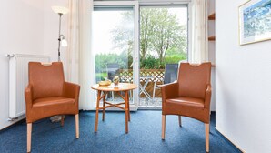 A room with two leather chairs, a small wooden table, and a floor lamp. - Double room with balcony or terrace - Double room in the Hotel-Pension (Neuharlingersiel)