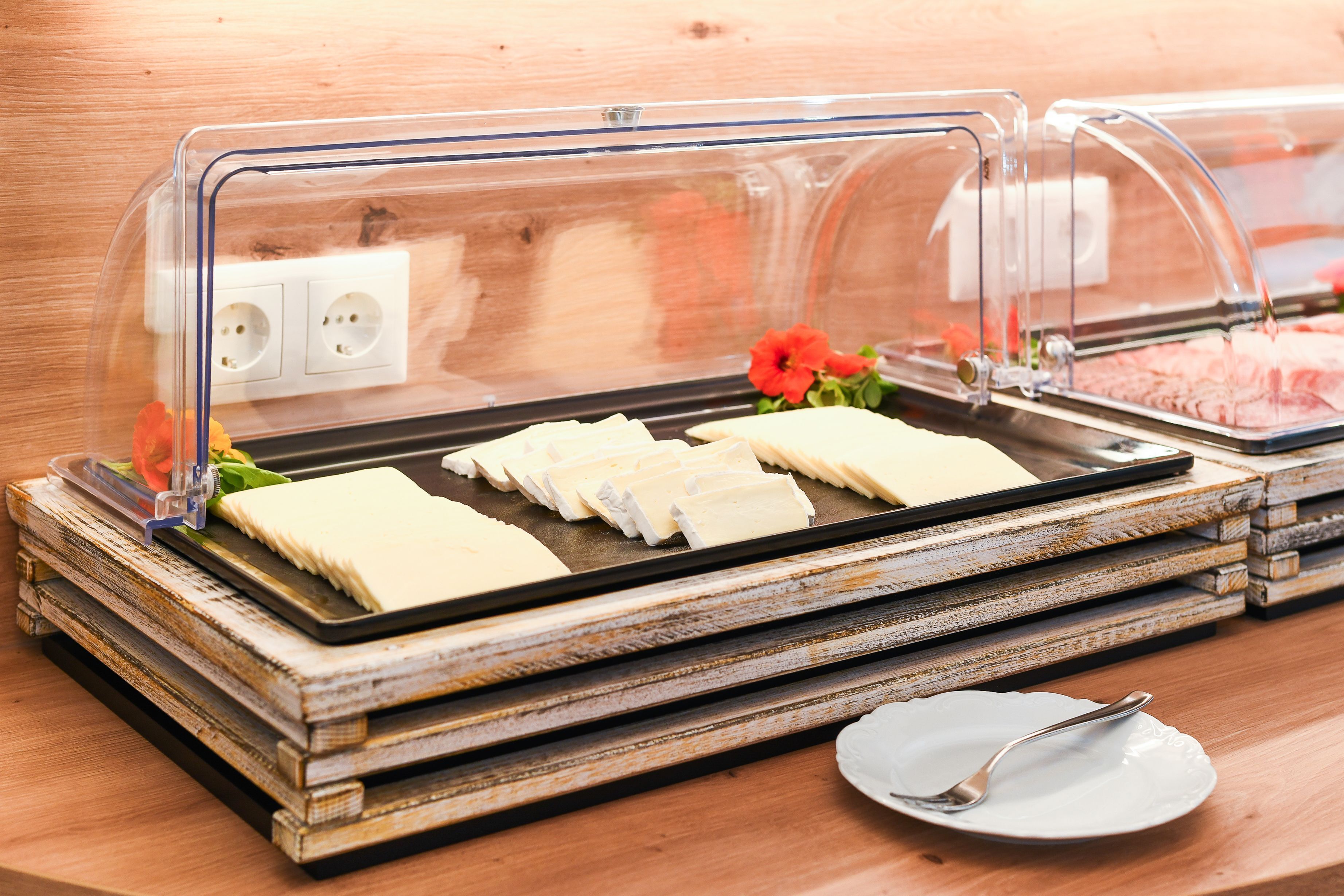 Una mesa de buffet con cubierta de vidrio transparente, un plato con cuchara y una decoración floral.