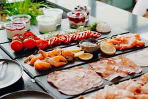 Fresh ingredients are arranged on a table, offering a selection of cured meats, sliced tomatoes, and dairy products.