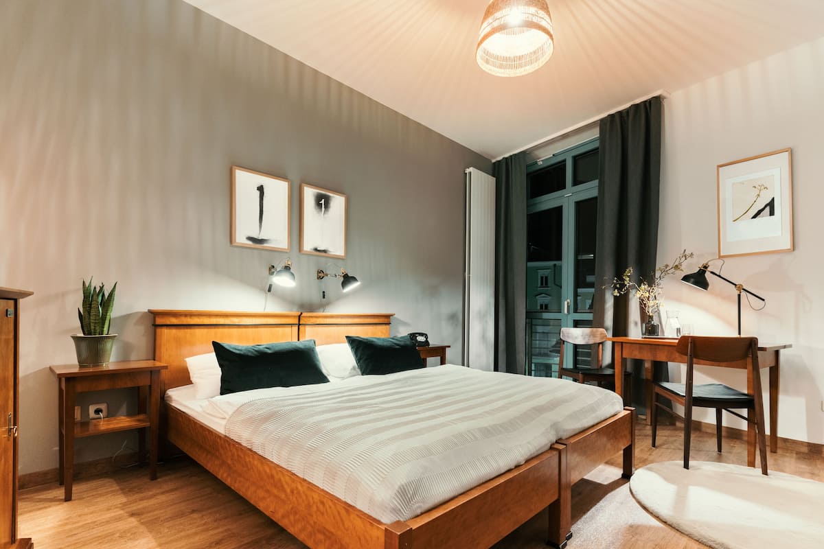 A modern bedroom with a wooden bed, bedside tables, a desk, and a chair.